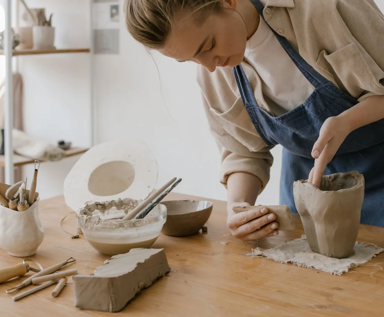 Mujer modelando arcilla sobre una mesa en un taller de cerámica