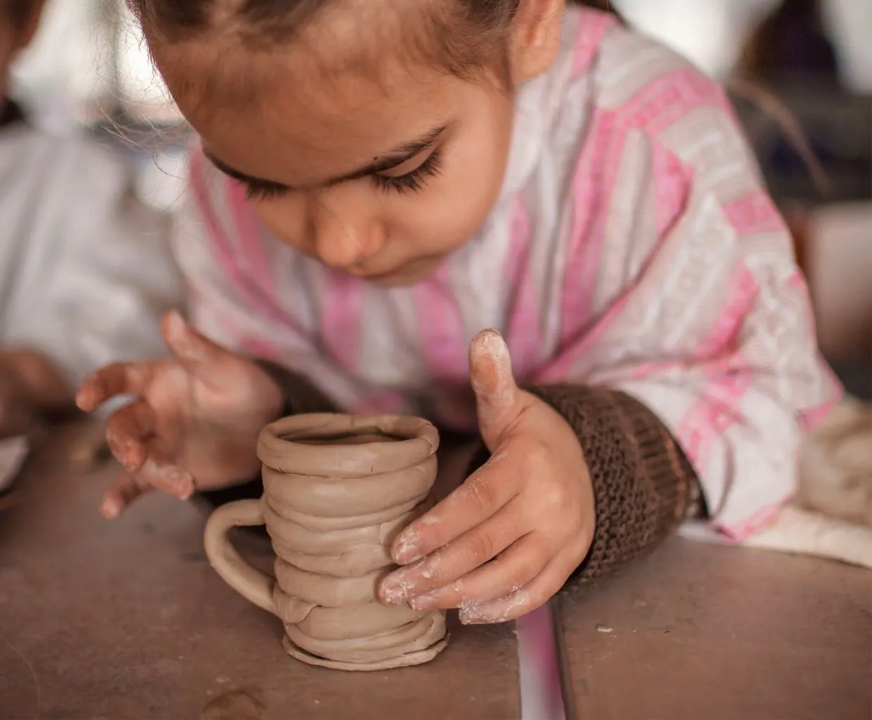 Niña modelando una figura de arcilla con las manos