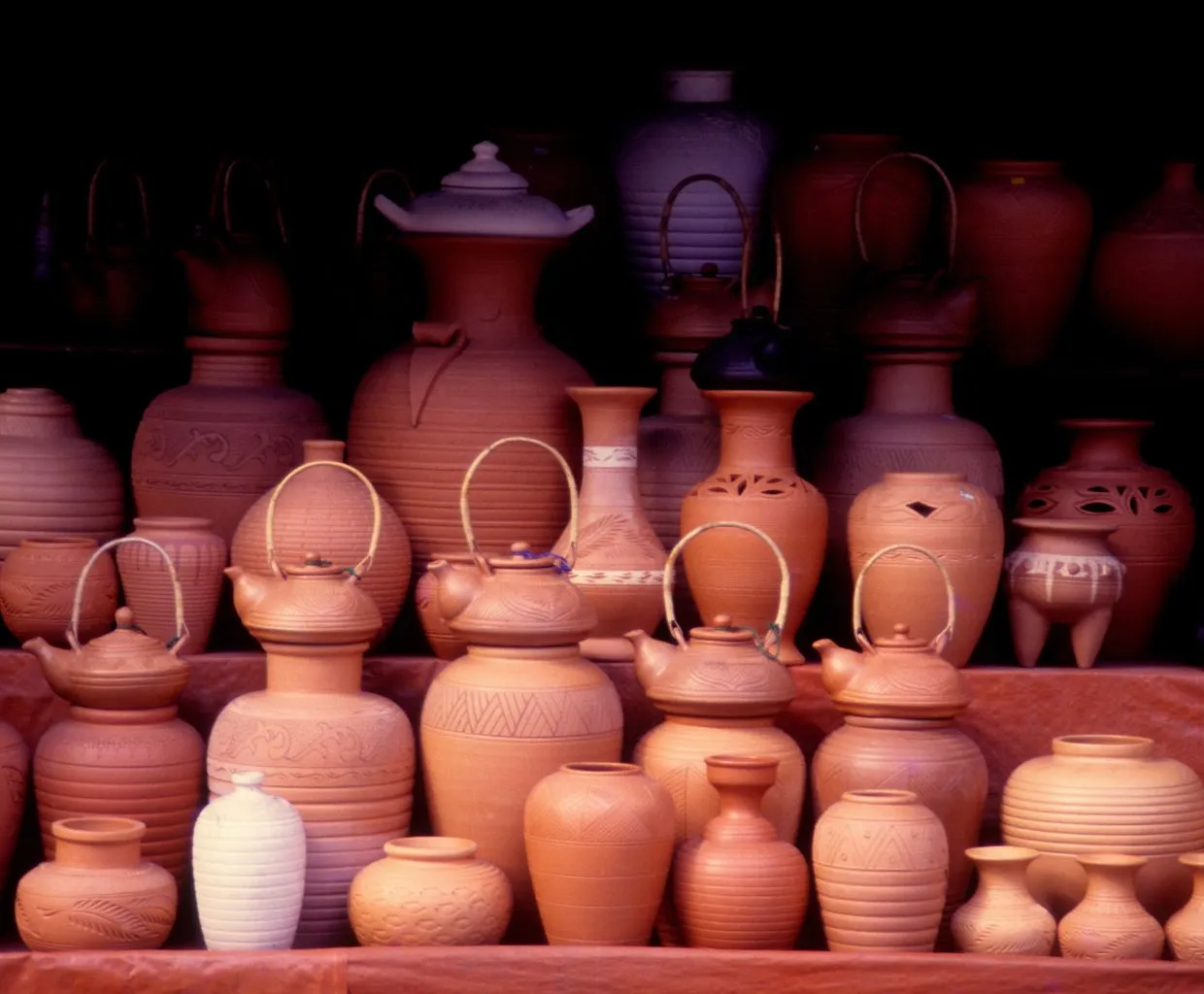 Vasijas de terracota rojizas sobre un fondo rosa