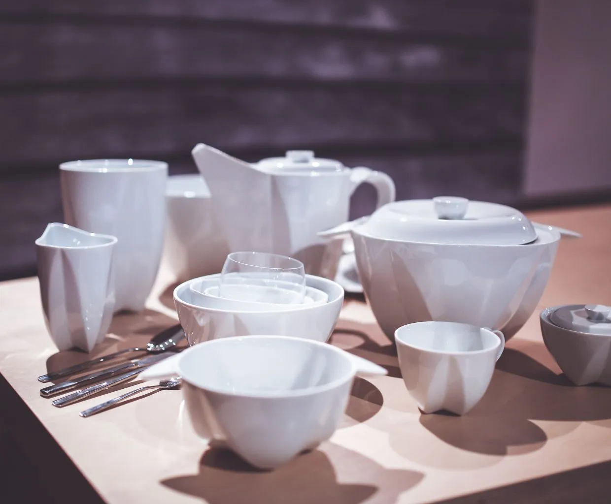 Vajilla blanca de cerámica con tazas, cuencos y tetera sobre una mesa